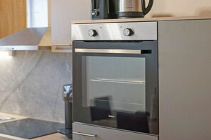 Eine moderne Küche mit eingebautem Backofen, einer Kaffeemaschine und einer Arbeitsplatte aus Edelstahl.