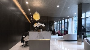 Una hall moderna con una reception in marmo, zona salotto e ampie finestre.