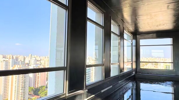 Interno di un grattacielo con ampie vetrate, un pavimento riflettente e vista sulla città.