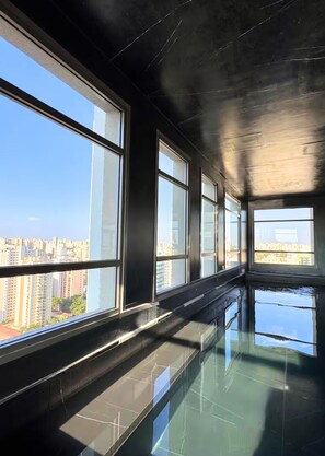 A high-rise interior with large windows, a reflective floor, and a view of a cityscape. - Grand Vitrali (São Paulo)