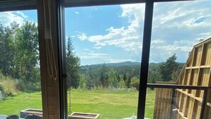 Un lit avec des serviettes enroulées, une terrasse en bois et une vue sur une piscine et une forêt.