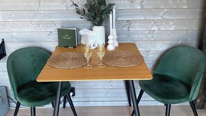 Une table en bois, deux chaises vertes, un vase avec des plantes et deux bougies.