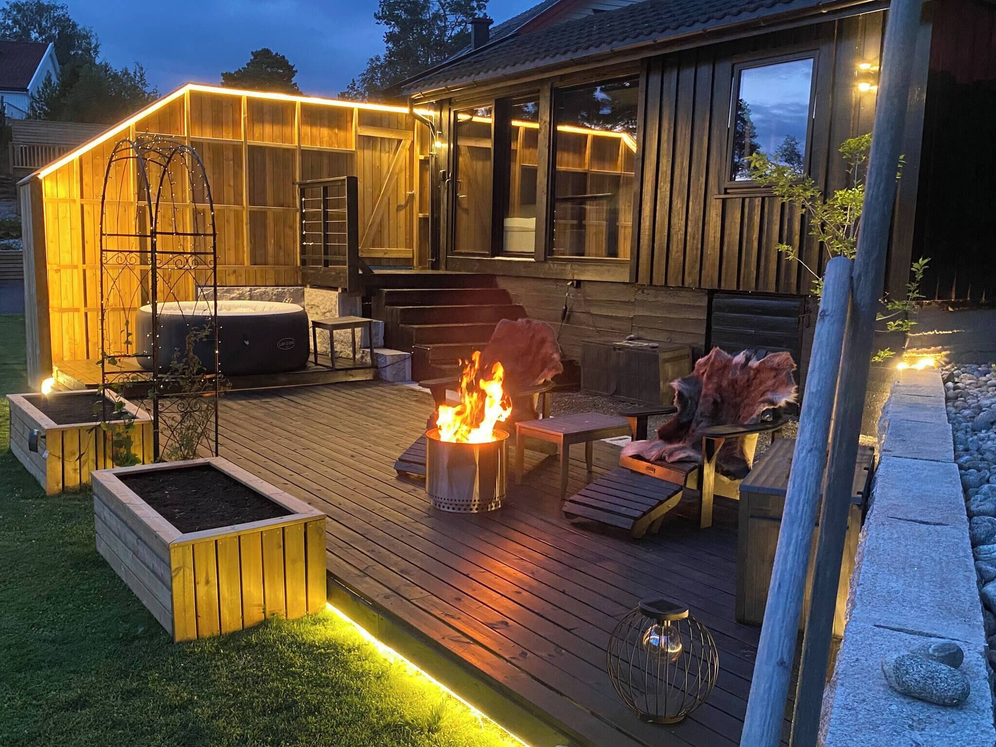 A wooden deck with a fire pit, outdoor seating, and a hot tub.
