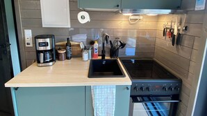 Une cuisine compacte équipée d’une cuisinière intégrée, d’un évier et d’une machine à café.