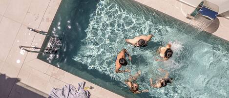 A rectangular swimming pool with clear water, a towel, and a glass of drink on the edge.