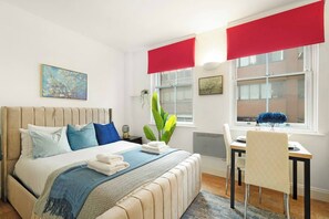 A bedroom with a bed, bedside table, chair, and a desk with a chair. - Cozy Studio in the Heart of the City of London A (London)