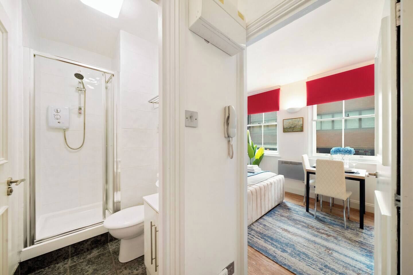 A bathroom with a shower, toilet, and a small window.