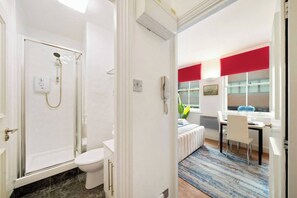 A bathroom with a shower, toilet, and a small window. - Cozy Studio in the Heart of the City of London A (London)