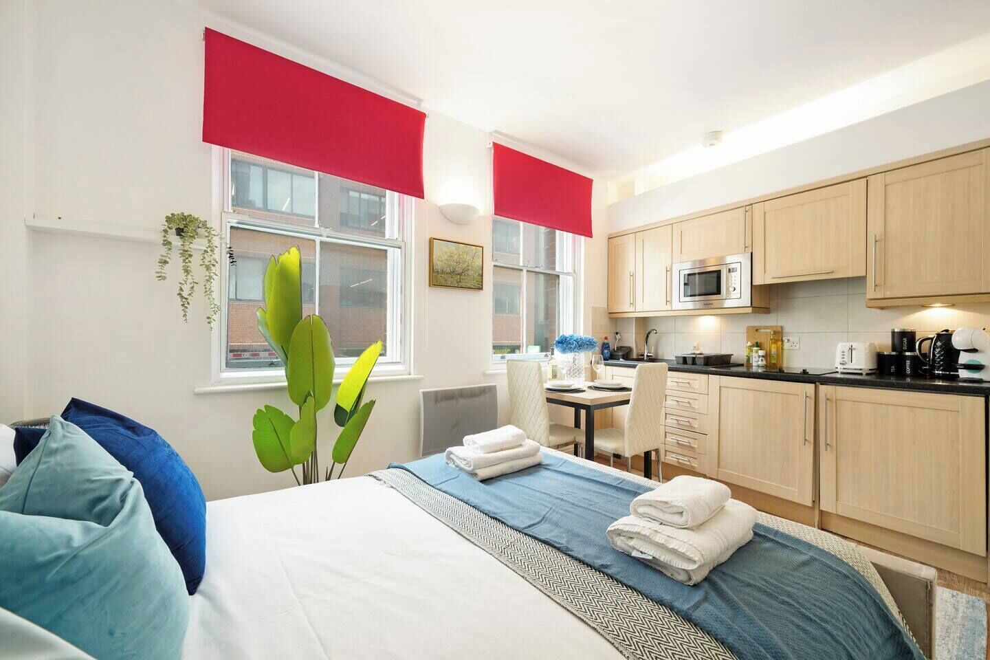 Een hotelkamer met een bed, bureau, magnetron en kitchenette.