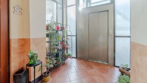 A hallway with a potted plant shelf, a door, and a tiled floor. - GuestHost - Cozy 70sqm apartment located on the second floor of a building with an elevator (NOT for disabled people)The apartment is situated in a quiet area of Turin, close to Parco Millefonti and the Po River, ideal for walks and outdoor activities. W (Turin)