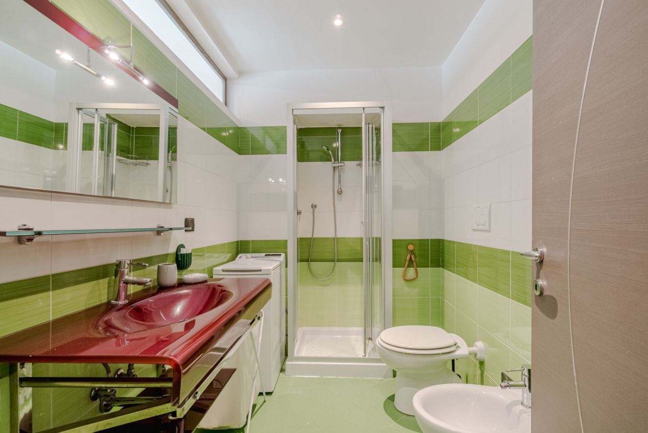 Ein Badezimmer mit Dusche, Toilette, Waschbecken und einer Duschkabine aus Glas.