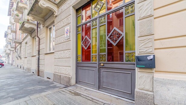 A building with ornate architectural details, a gated entrance, and a mailbox on the wall. - GuestHost - Cozy 70sqm apartment located on the second floor of a building with an elevator (NOT for disabled people)The apartment is situated in a quiet area of Turin, close to Parco Millefonti and the Po River, ideal for walks and outdoor activities. W (Turin)