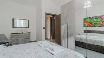 Una camera da letto moderna con un letto grande, una cassettiera, uno specchio e un'opera d'arte originale al muro.