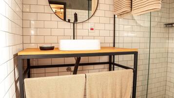 A bathroom with a white sink, a mirror, and two towels hanging on a rack.