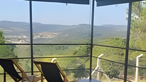 Un espace extérieur abrité, aménagé avec des sièges, et offrant une vue sur un paysage vallonné.