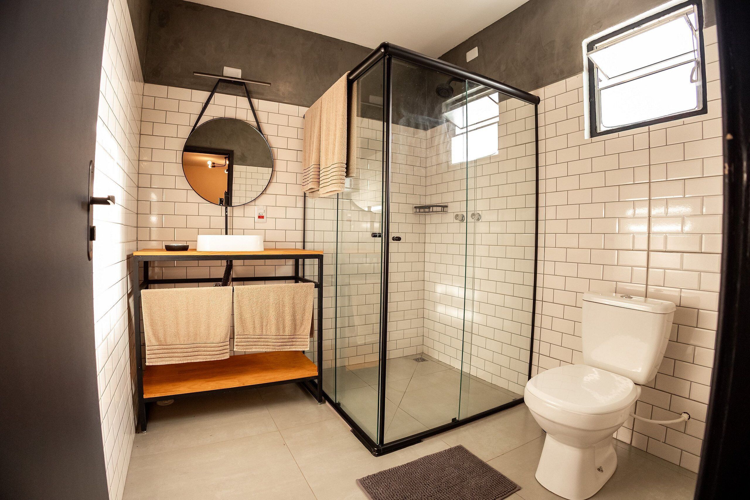 A modern bathroom with a glass shower enclosure, a toilet, a sink with a mirror, and a towel rack.