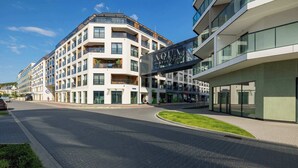 Un hotel moderno con un letrero llamativo, varios balcones y una calle pavimentada y limpia.