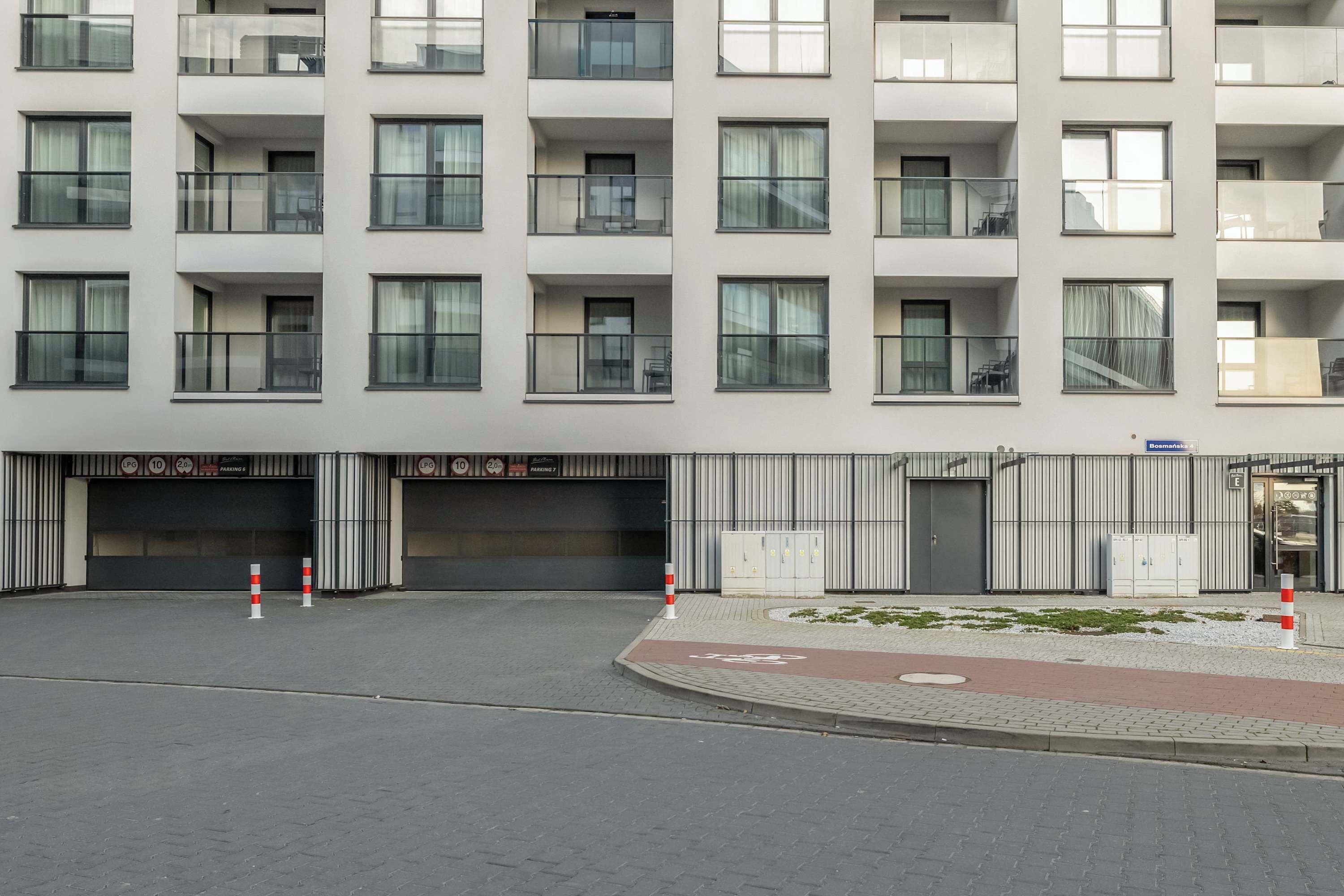 Un immeuble moderne à plusieurs étages, doté de balcons, de grandes fenêtres et d’une entrée sécurisée par un portail.