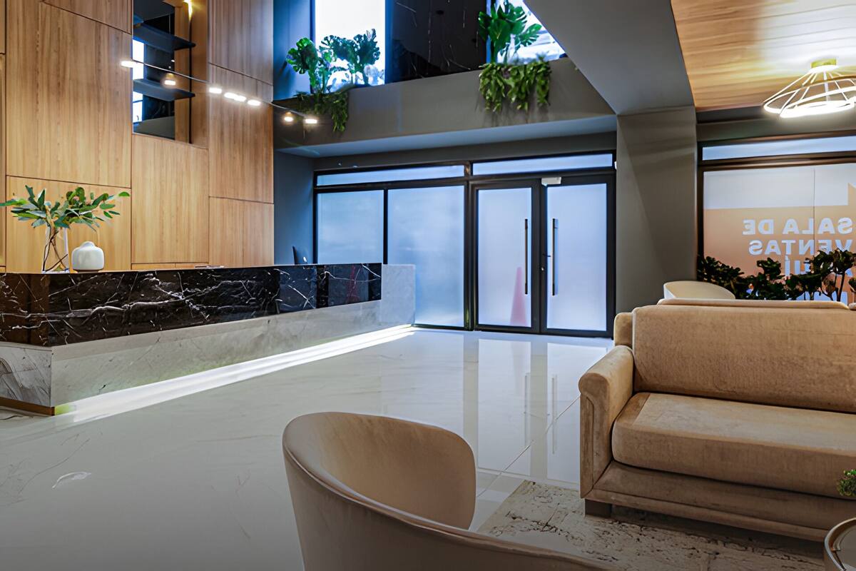 A modern lobby with a marble reception desk, a sofa, and a large glass door entrance.