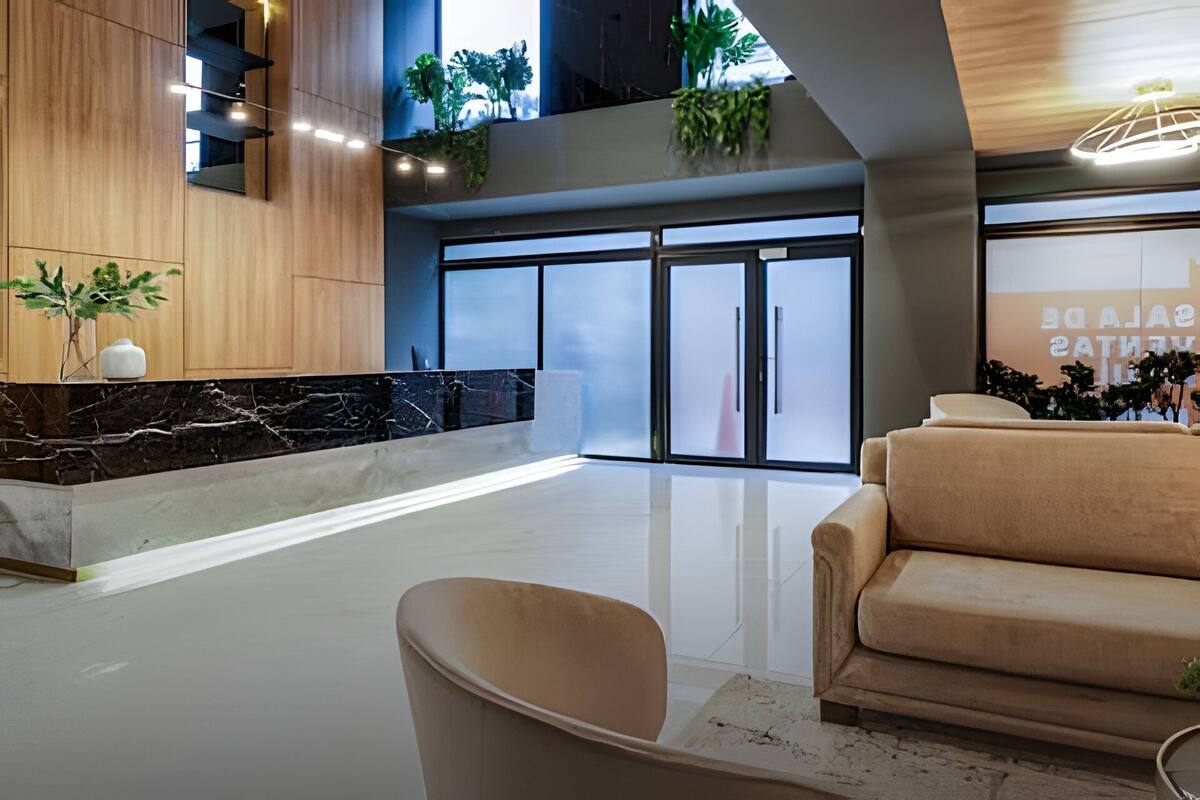 A spacious lobby with a marble reception desk, a beige sofa, and a large glass door entrance.