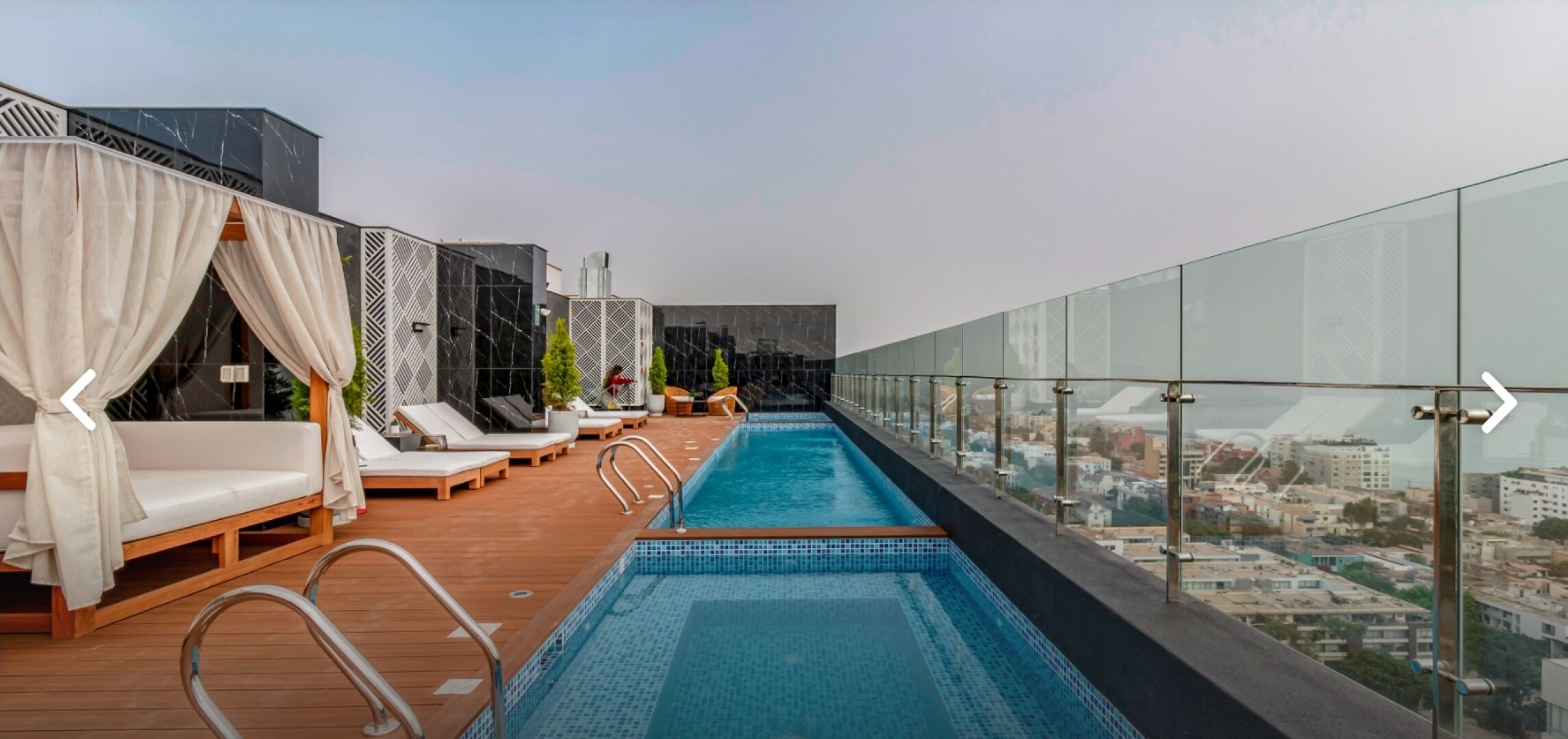 Una piscina al aire libre, sombrillas, sillones reclinables de piscina