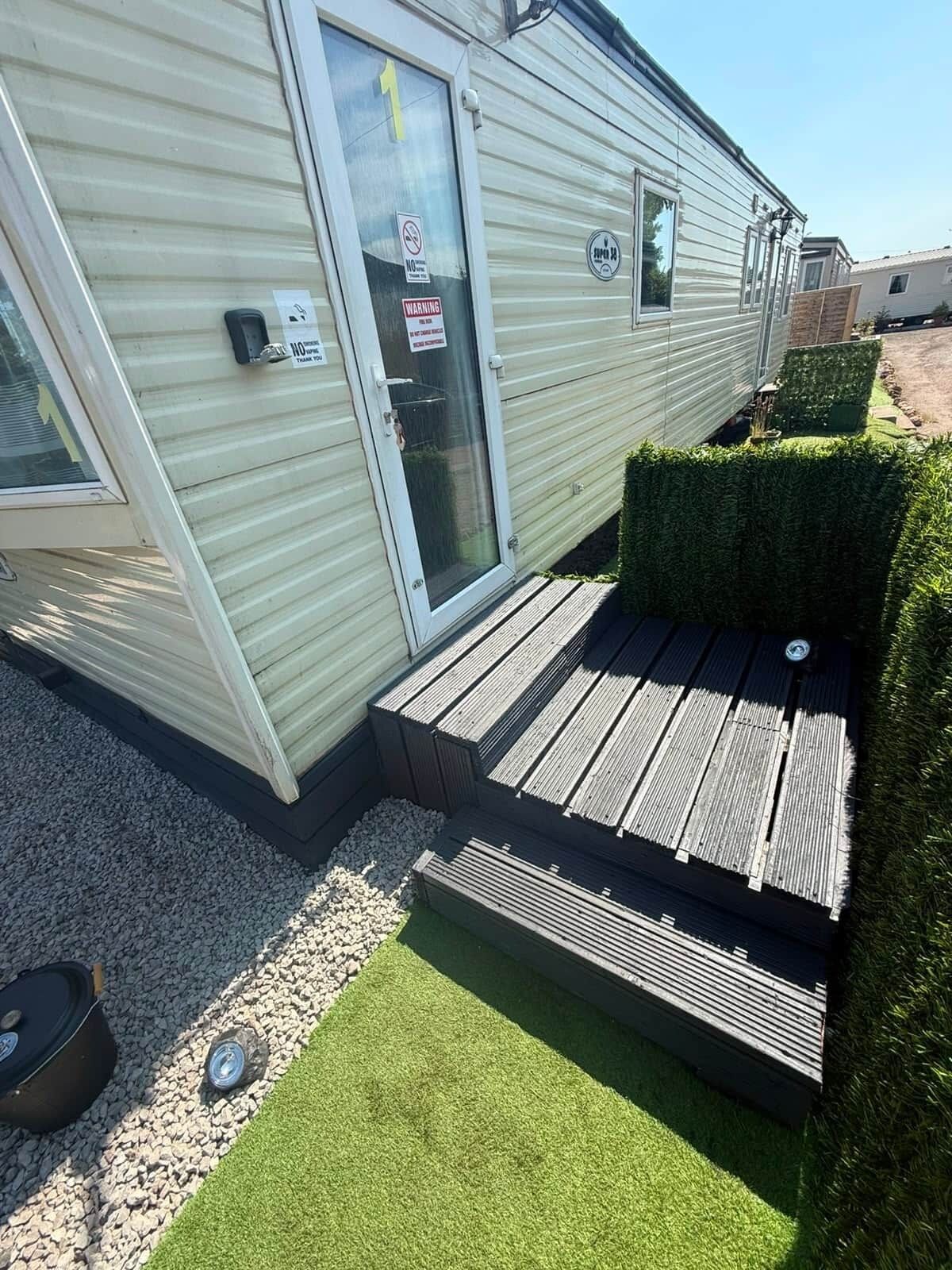 Une maison mobile avec une porte, un petit porche et une allée gravillonnée.