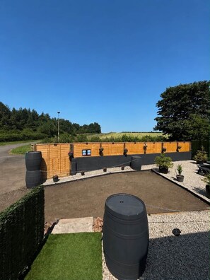 Un espace extérieur clos, doté d’un sol en gravier, entouré d’une clôture en bois et agrémenté de plantes en pot.