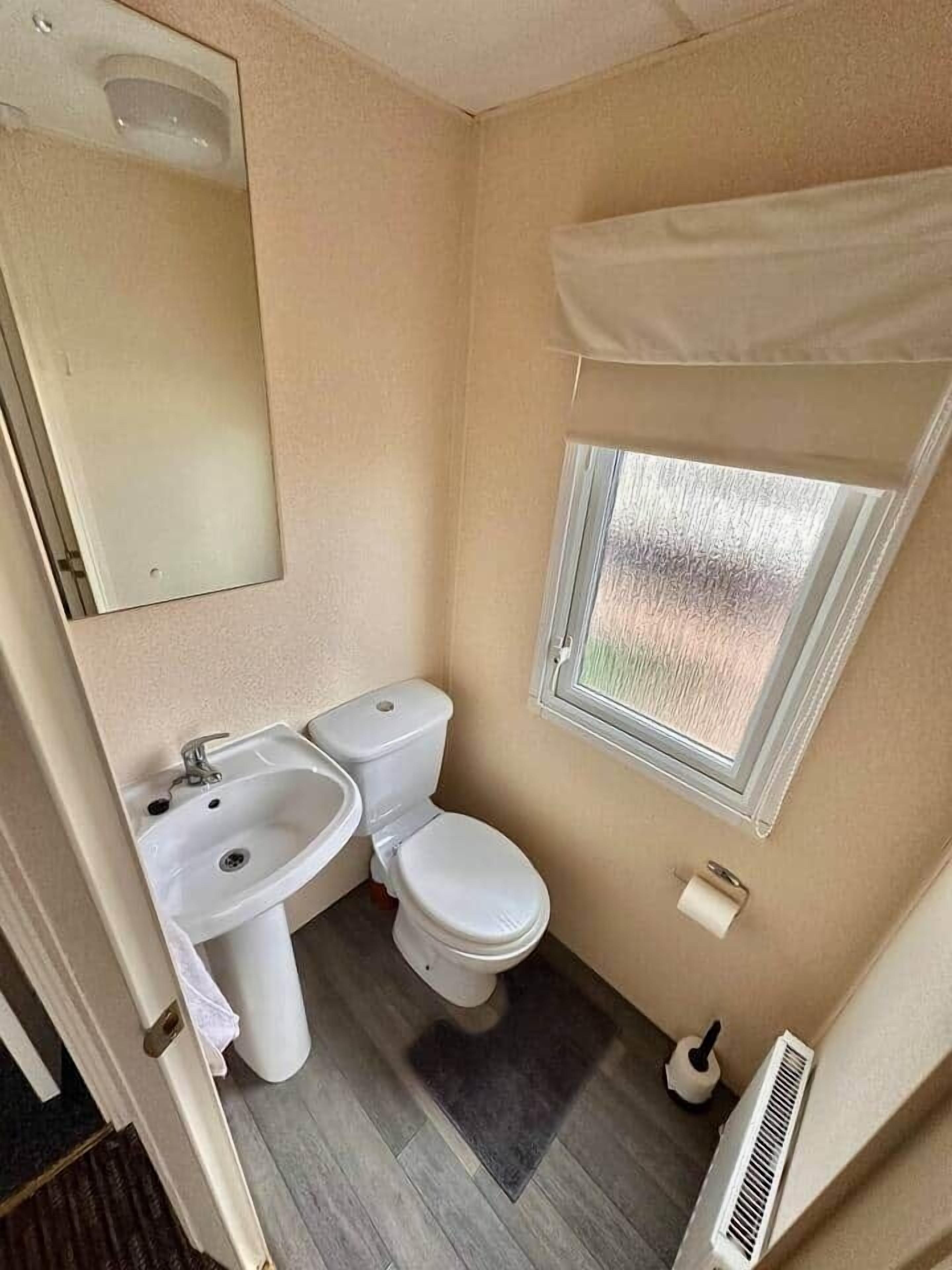 Un bagno compatto con servizi igienici, lavandino e finestra.