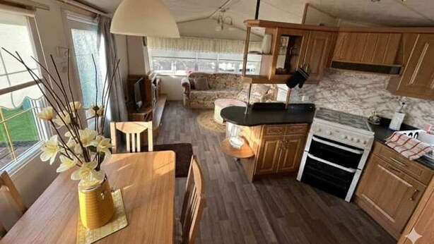 Una cocina compacta con armarios de madera, una estufa y un comedor con mesa y sillas.