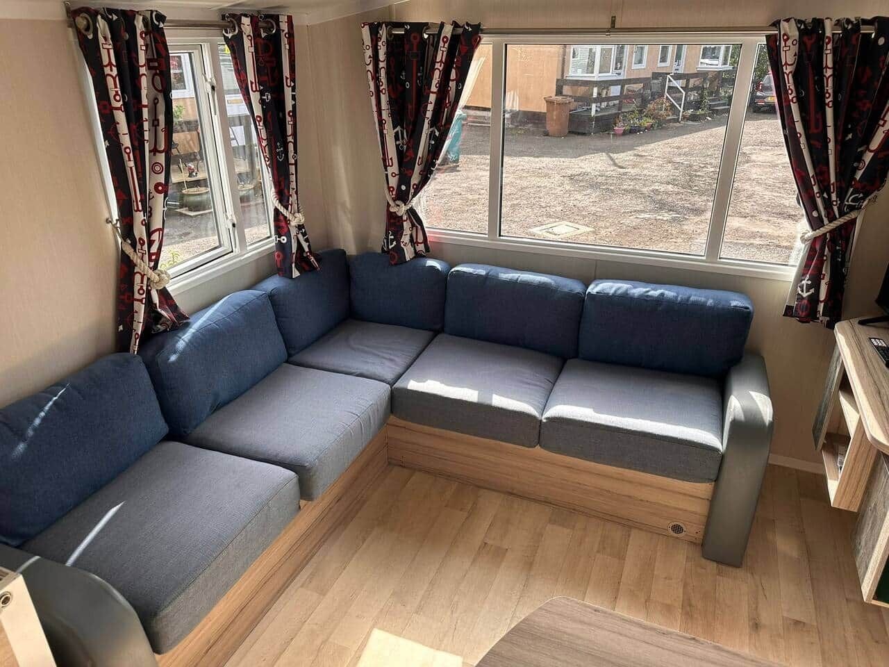 Een kamer met een modulaire bank, een houten vloer en gordijnen.