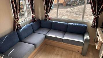 Een kamer met een modulaire bank, een houten vloer en gordijnen.
