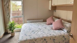 Une chambre à coucher avec un lit, un radiateur, une fenêtre avec des rideaux et une plante en pot.
