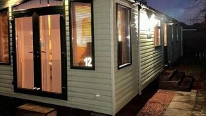 Une petite maison mobile d’un seul étage, dotée d’un porche et d’une plaque portant le numéro « 12 ».