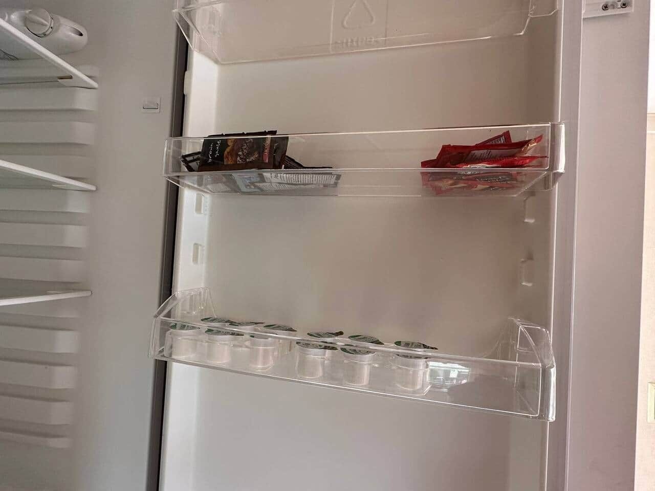 Ett förvaringsskåp med flera fack, inklusive en nedre hylla med genomskinliga plastbehållare och en mellanhylla med böcker och små föremål.