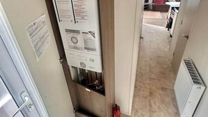 A hallway with a water heater, a door, and a radiator. - Delta, Bromley 4-Bedroom Caravan (Uddingston)
