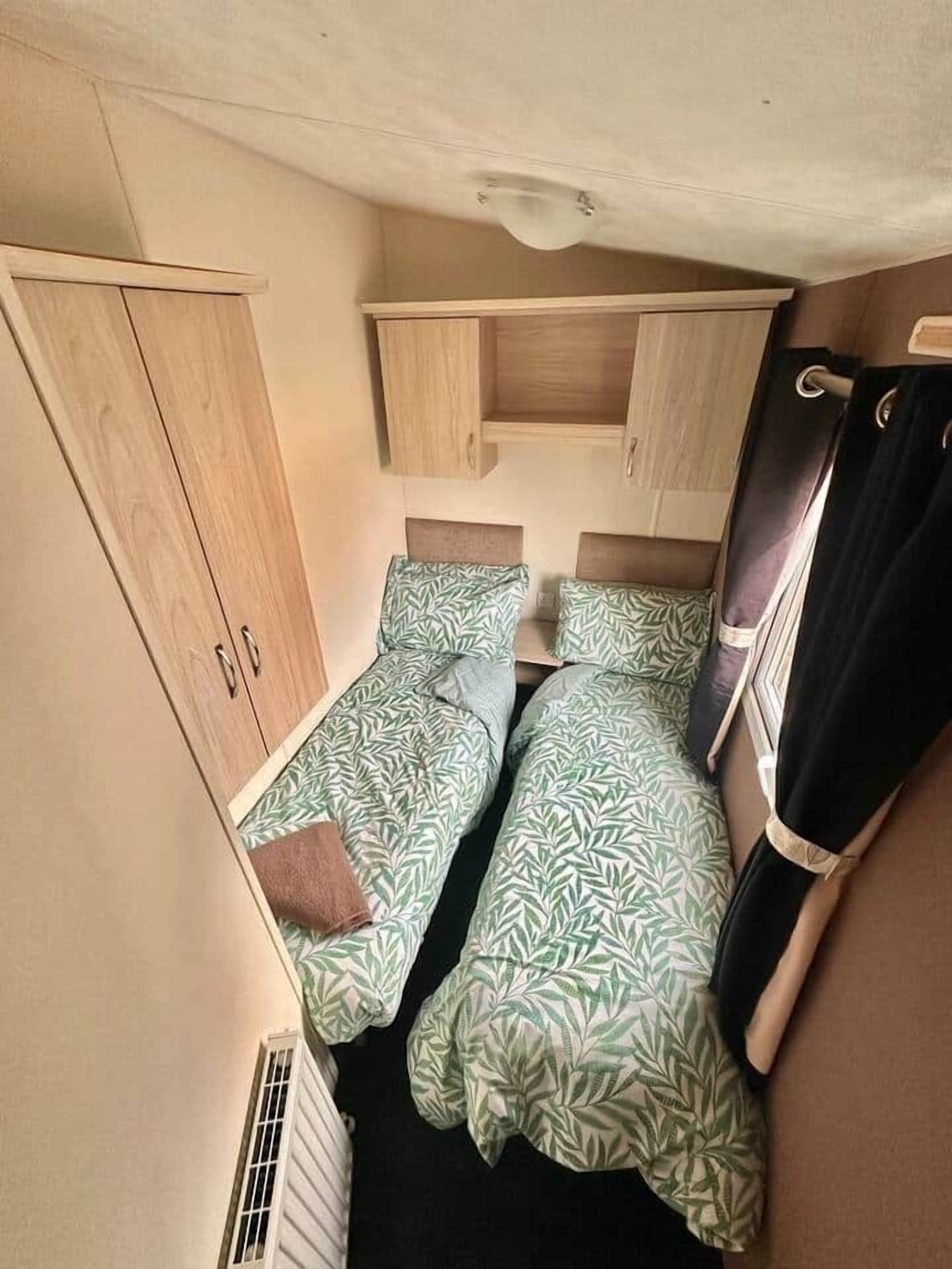 A compact room with two single beds, a wardrobe, and a small table.