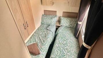 A compact room with two single beds, a wardrobe, and a small table.
