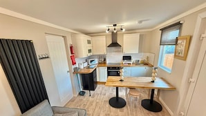 A compact kitchen with a dining area, a sofa, and a window with a view.