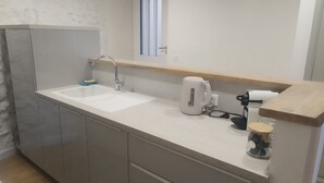 Una cocina con un lavamanos doble, un hervidor y una cafetera en la encimera.