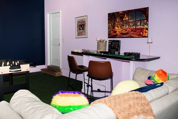A cozy living room with a sofa, chairs, a foosball table, and a fireplace.