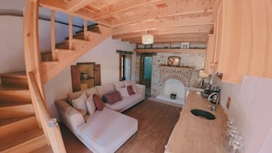Un interno in legno con una scala, un divano, un camino e una zona cucina.