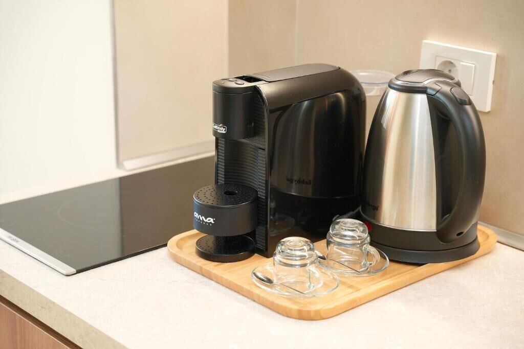 A kitchen with a coffee maker, a kettle, and a toaster on a wooden tray.