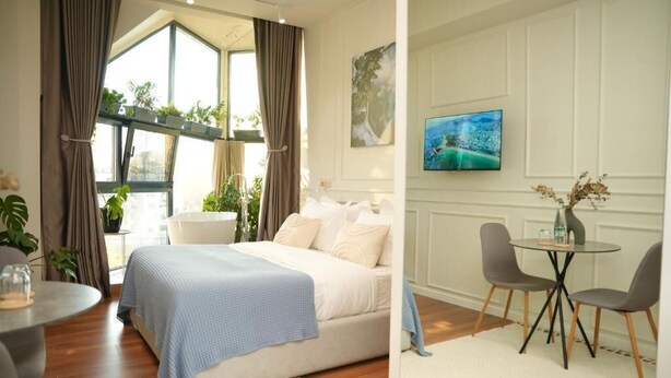 Une chambre à coucher avec un lit, une table à manger avec des chaises, un téléviseur et une fenêtre avec des rideaux.