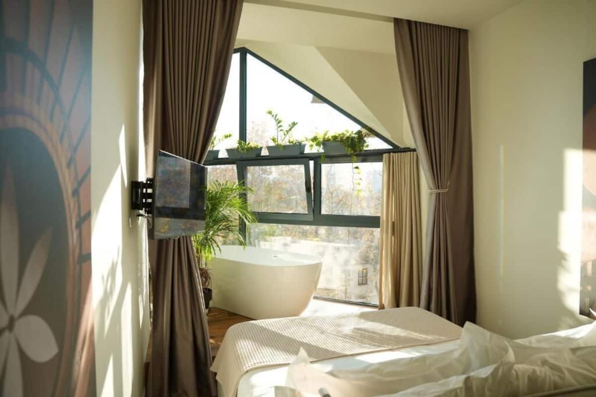 Ein Schlafzimmer mit großem Fenster, einer Badewanne und einem Bett.