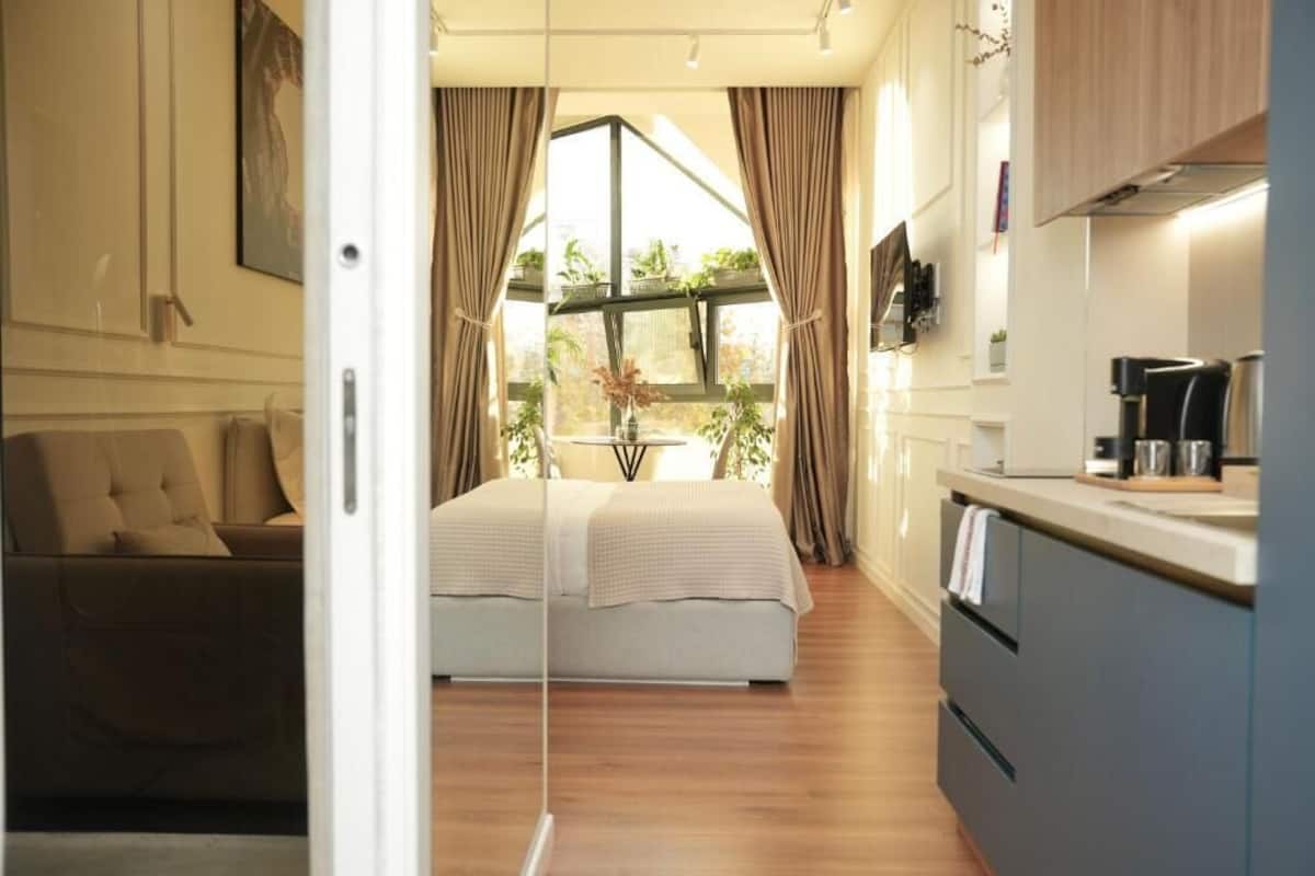Ein modernes Schlafzimmer mit großem Bett, einer Sitzecke und einer Küchenzeile mit Blick aus dem Fenster.