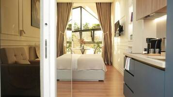 Een moderne slaapkamer met een groot bed, een zithoek en een keuken met uitzicht.