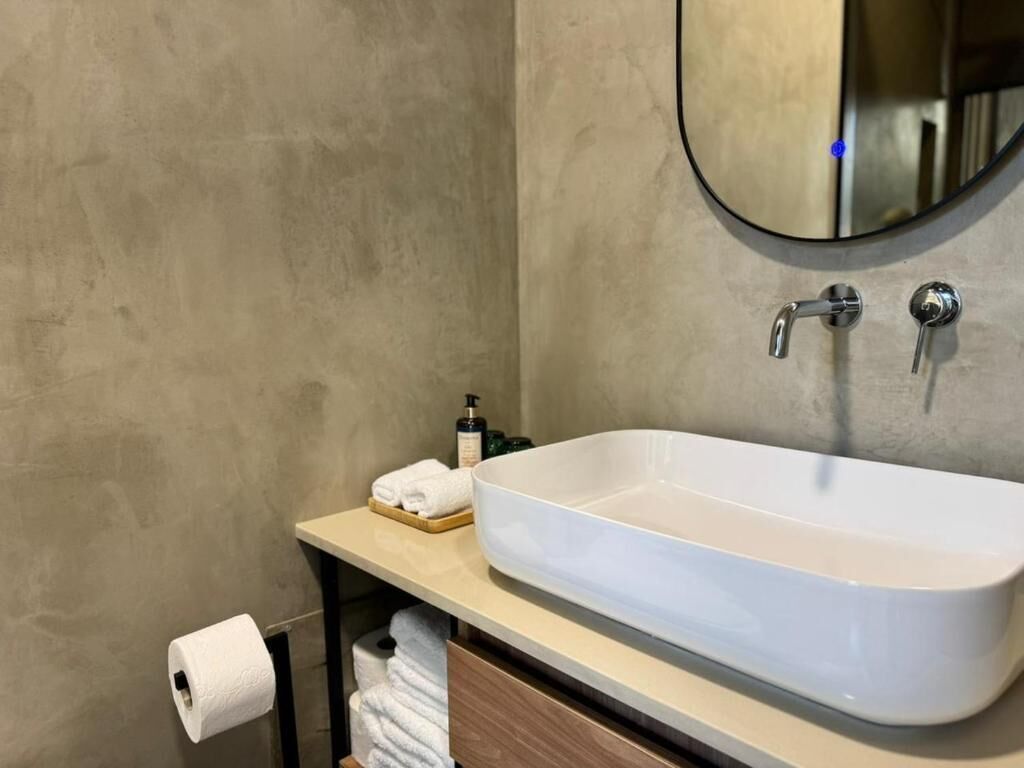 A bathroom with a large white sink, a mirror, and a towel rack.