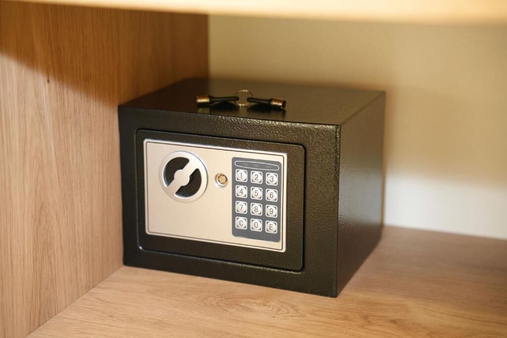 A black safe with a keypad lock on a wooden shelf.