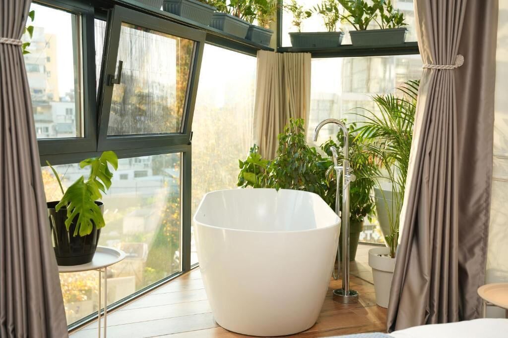 A modern bathroom with a freestanding bathtub, a sink, and potted plants.