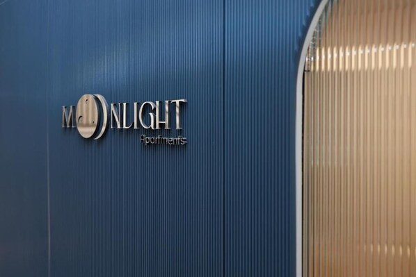 A sign for "MONLIGHT Apartments" on a blue wall.